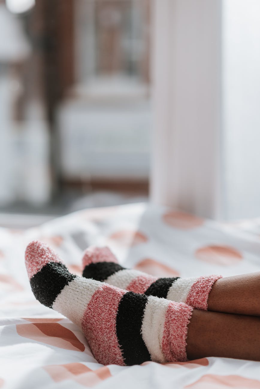 crop black woman in striped socks on bed blanket